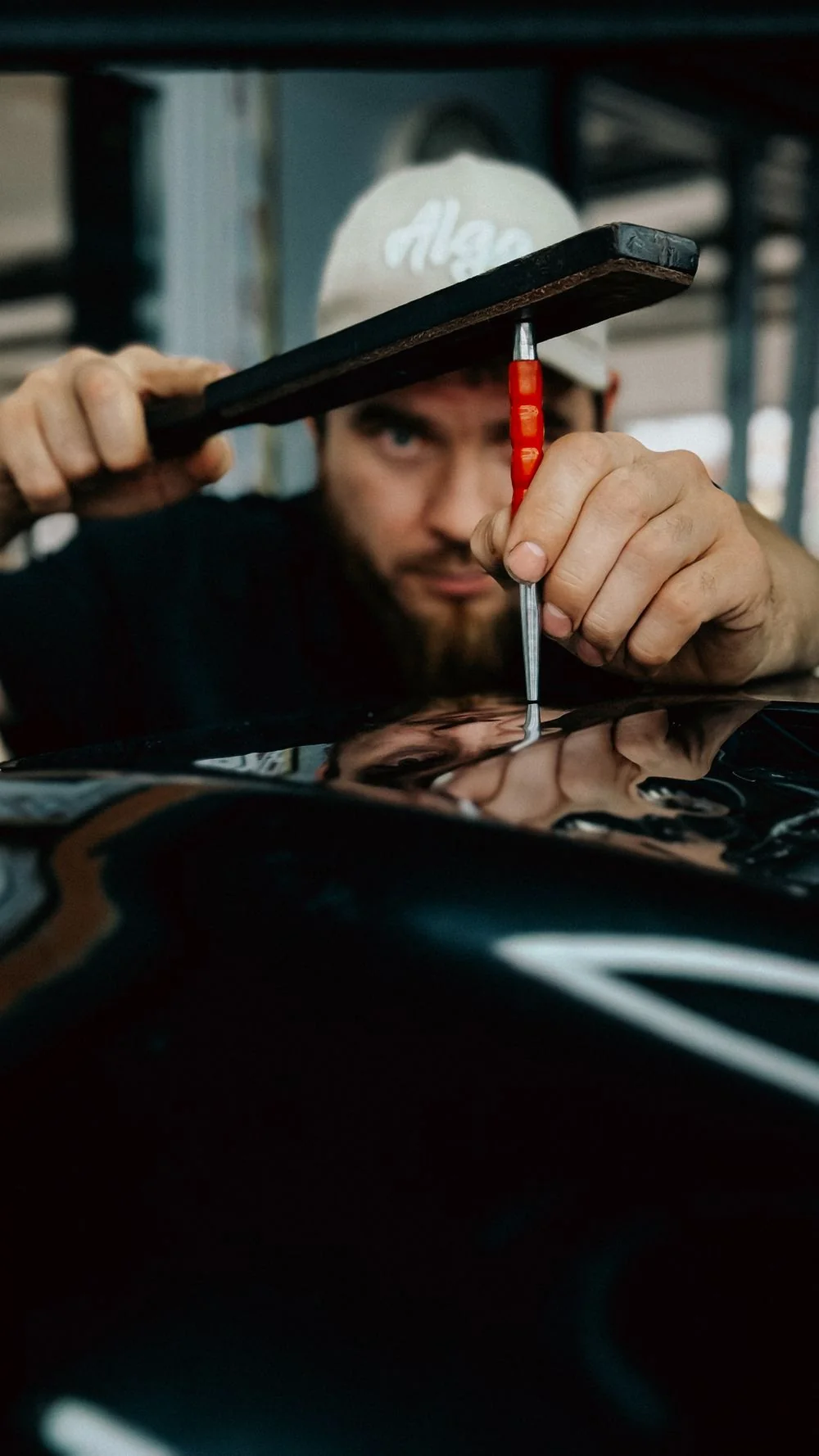 Technician performing paintless dent repair on a car hood